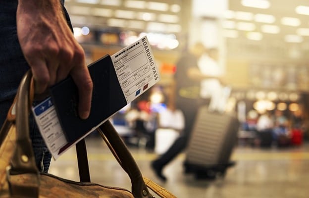 A hand holding a bag and a boarding pass